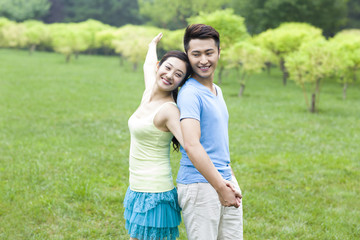Sweet young couple in park, back to back