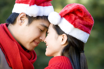 Young Couple Rub Noses while Wearing Santa Hats