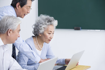 Senior adults having computer class at school