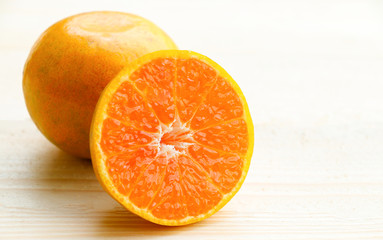 Organic orange fruit. Slices on soft wooden background