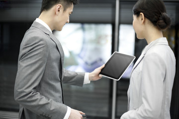 Young business partners with digital tablet on subway platform