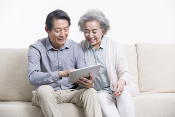Senior couple playing digital tablet in living room