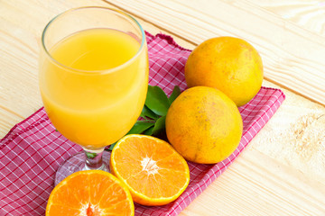 Glass of orange juice with orange slice on soft wooden background