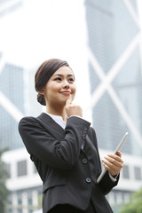 Cheerful businesswoman hand on chin with digital tablet in hand, Hong Kong