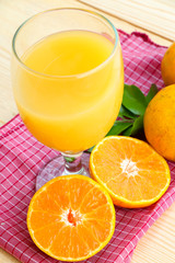 Glass of orange juice with orange slice on soft wooden background