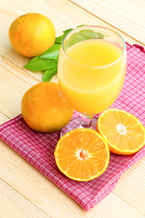 Glass of orange juice with orange slice on soft wooden background
