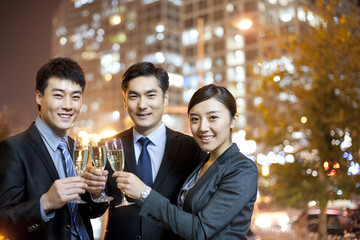 Chinese business people toasting champagne with city lights in the background