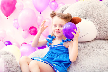 Obraz na płótnie Canvas Cheerful girl plays with balloon in playroom