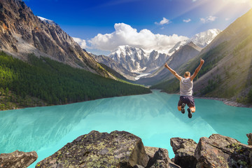 Beautiful mountain landscape with lake and jumping man.  Extreme sports concept.