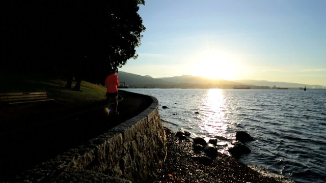 Male jogger running Pacific harbor coastal path sunset Vancouver 
