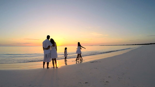 Happy Caucasian family enjoying beach vacation at sunset