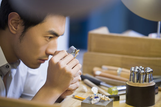 Close up of jeweler examining jewelry with loupe