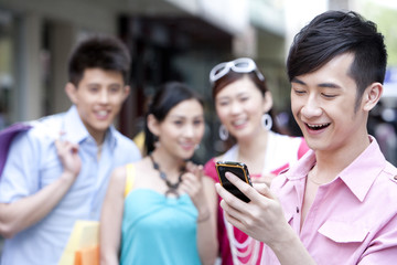 Young man using phone in front of friends