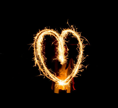 people draw heart image with firework on black background