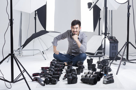Fototapeta Photographer in studio with many cameras on the ground