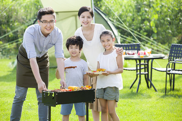 Naklejka na ściany i meble Young family barbecuing outdoors