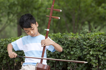 Little boy playing erhu outdoors