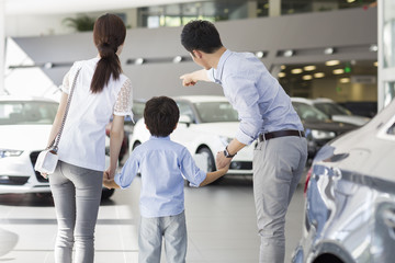 Young family looking at new car in showroom