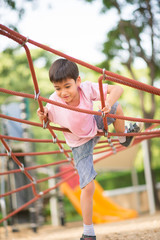 Obraz premium Little boy climbing on the rope at playground