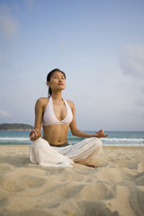 Fototapeta na wymiar Young woman doing yoga on the beach