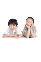 Happy siblings lying on front, studio shot