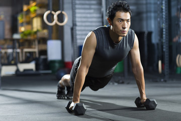 Man doing push ups exercise with dumbbell