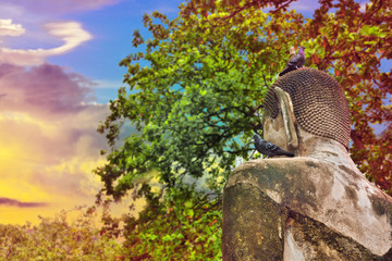 behind old bhudda with rainbow light filter
