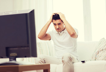 disappointed man watching tv at home