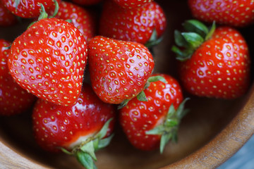 Close-up strawberry in a wooden bowl on a gray background