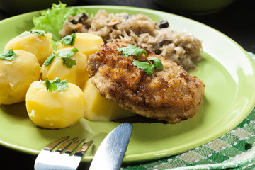Fried pork schnitzel served with boiled potatoes and fried sauer
