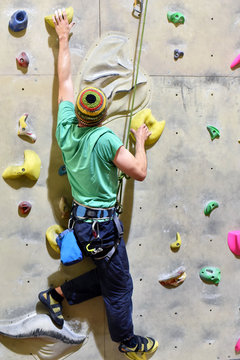 Mann klettert in einer Indoor-Kletterhalle die Wand hoch