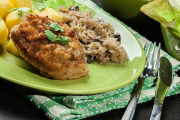 Fried pork schnitzel served with boiled potatoes and fried sauer