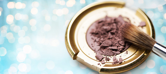 close up of makeup brush and eyeshadow over lights