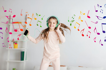 girl jumping on bed with smartphone and headphones