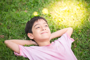 Little boy laying down on the grass dreaming light - Powered by Adobe