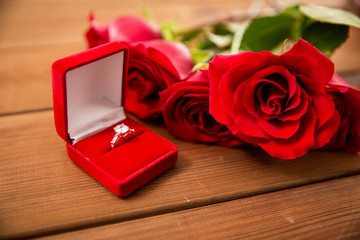 close up of diamond engagement ring and red roses