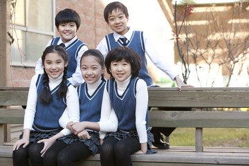 Five classmates sitting on a school bench