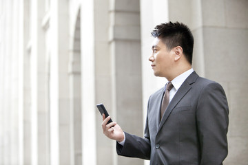 Obraz na płótnie Canvas Happy mature businessman with a smart phone outdoors, Hong Kong