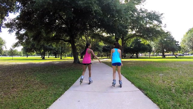 Young slim multi ethnic females inline skating in park