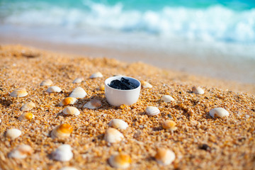 Dead sea mud for spa treatments in a cup on the beach