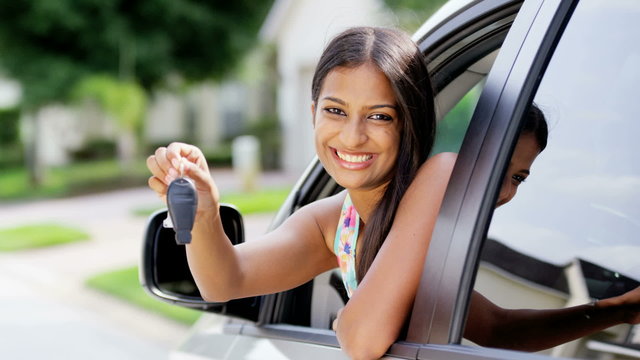 Portrait of young happy Asian Indian female smiling holding car key in car