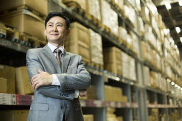 Confident businessman arms crossed in warehouse