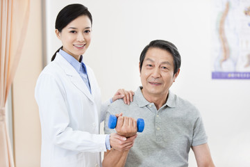 Senior patient exercising with dumbbell under doctor's help