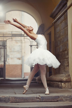 Perfect lines. Portrait of a talented ballet dancer woman leaning back standing in an archway outdoors