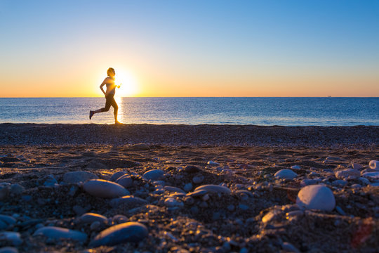 Human Silhouette jogging along Ocean Beach at Sunrise