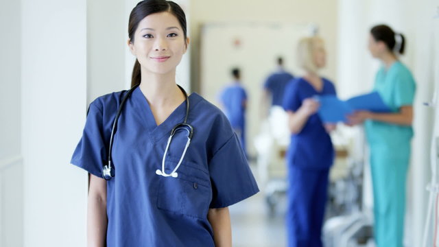 Portrait of confident Asian American female nurse in medical centre corridor