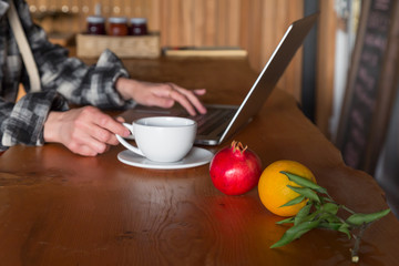 Person working on Computer at wooden Table with Fruits on foreground