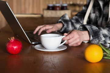 Person working on Computer at wooden Table with Fruits on foreground