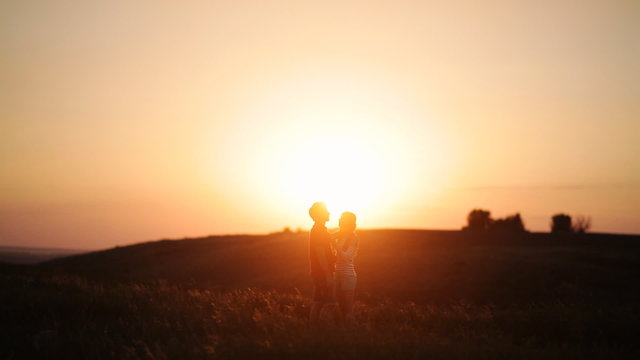 young couple embracing in the sunset light in the grass
