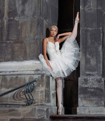 Obraz premium Reaching for dreams. Portrait of a beautiful female ballerina posing near an old castle with her leg raised up against the wall soft focus